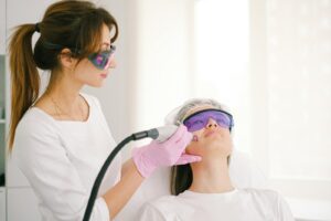 Une cosmétologue effectuant un traitement au laser sur une femme dans une clinique.