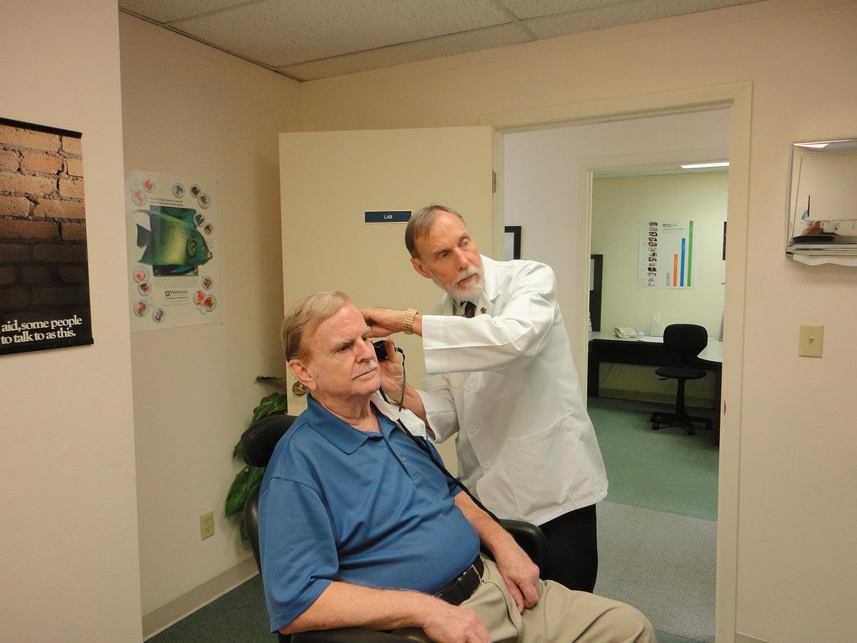 Un médecin en blouse blanche examine le visage d'un patient assis