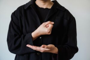 Une personne en noir montre les paumes ouvertes, gestes précis