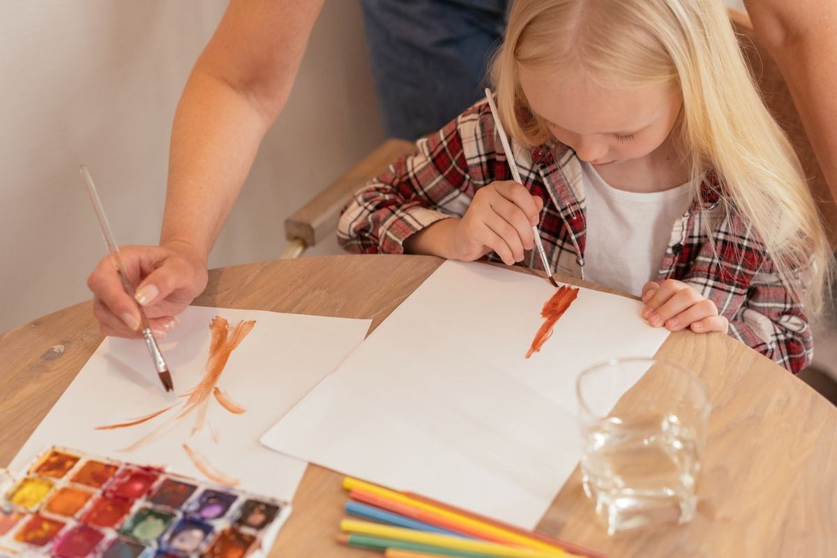 Enfant et adulte créent des œuvres d'art avec des aquarelles et des crayons