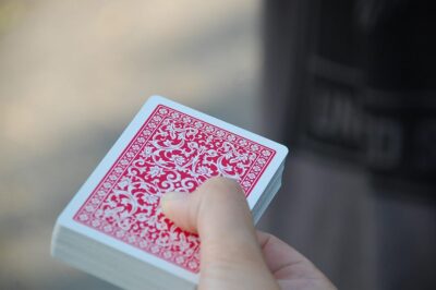 Une main tient un jeu de cartes à dos rouge, flou extérieur