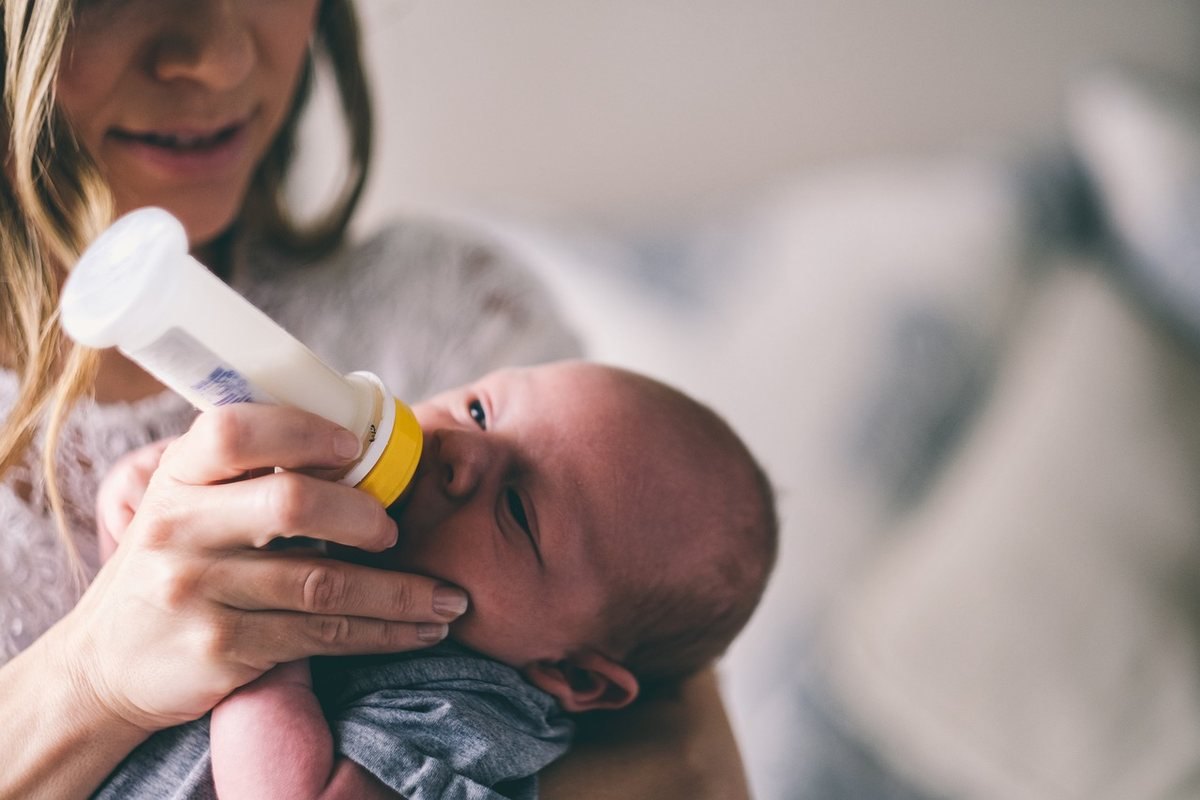 Une femme allaite son bébé avec un biberon dans un cadre intérieur