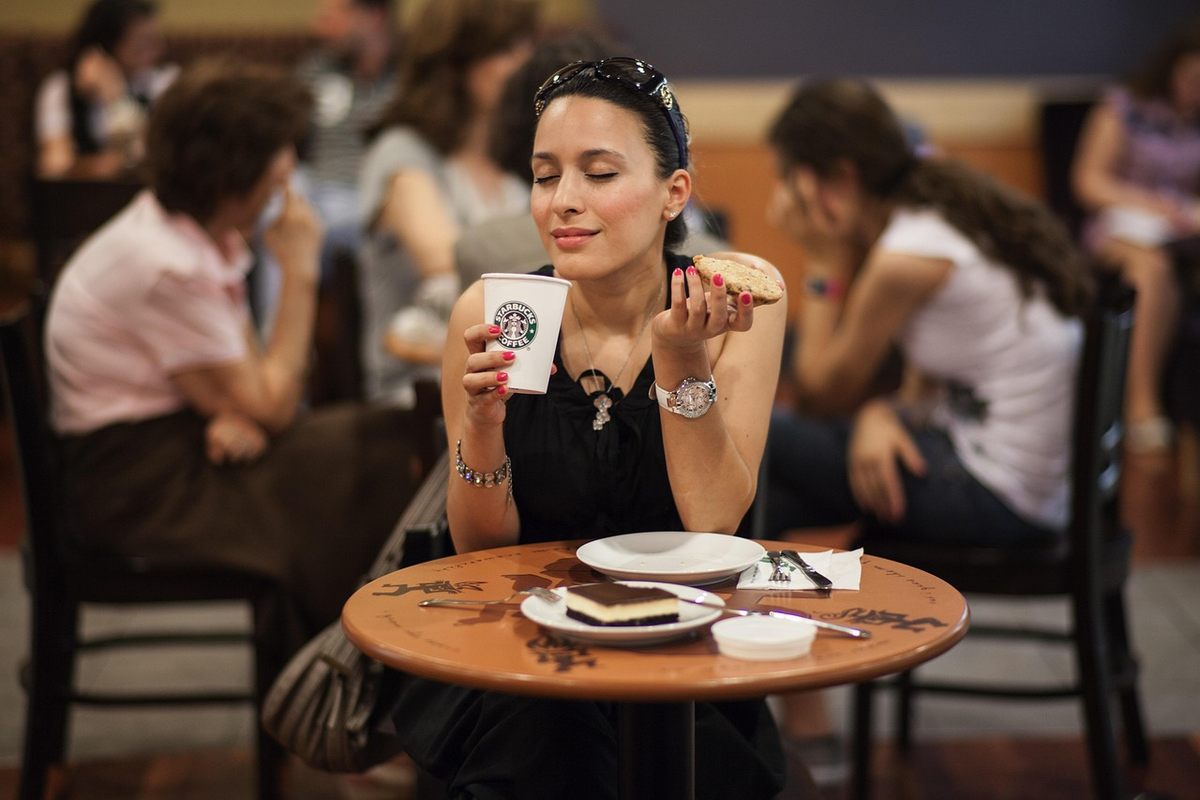 Une femme boit un café dans un café, assied à une table ronde