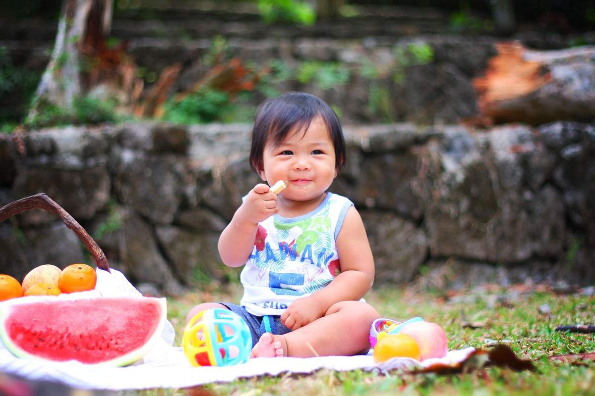 Un enfant mange un morceau de fruit lors d'un pique-nique en plein air