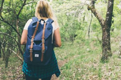 Une femme porte un sac à dos bleu et avance dans une forêt